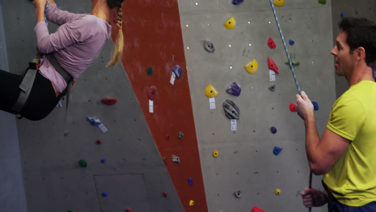 ayudando a una mujer a escalar la pared artificial 4k