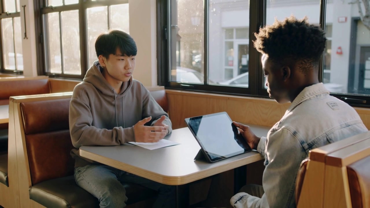 Two Young Men Having a Discussion at a Cafe Table