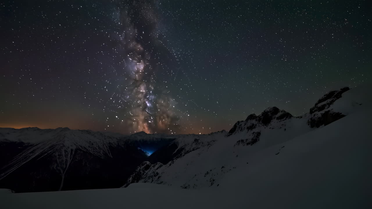 Time Lapse of Milky Way and Stars Over Snowy Mountains at Dawn