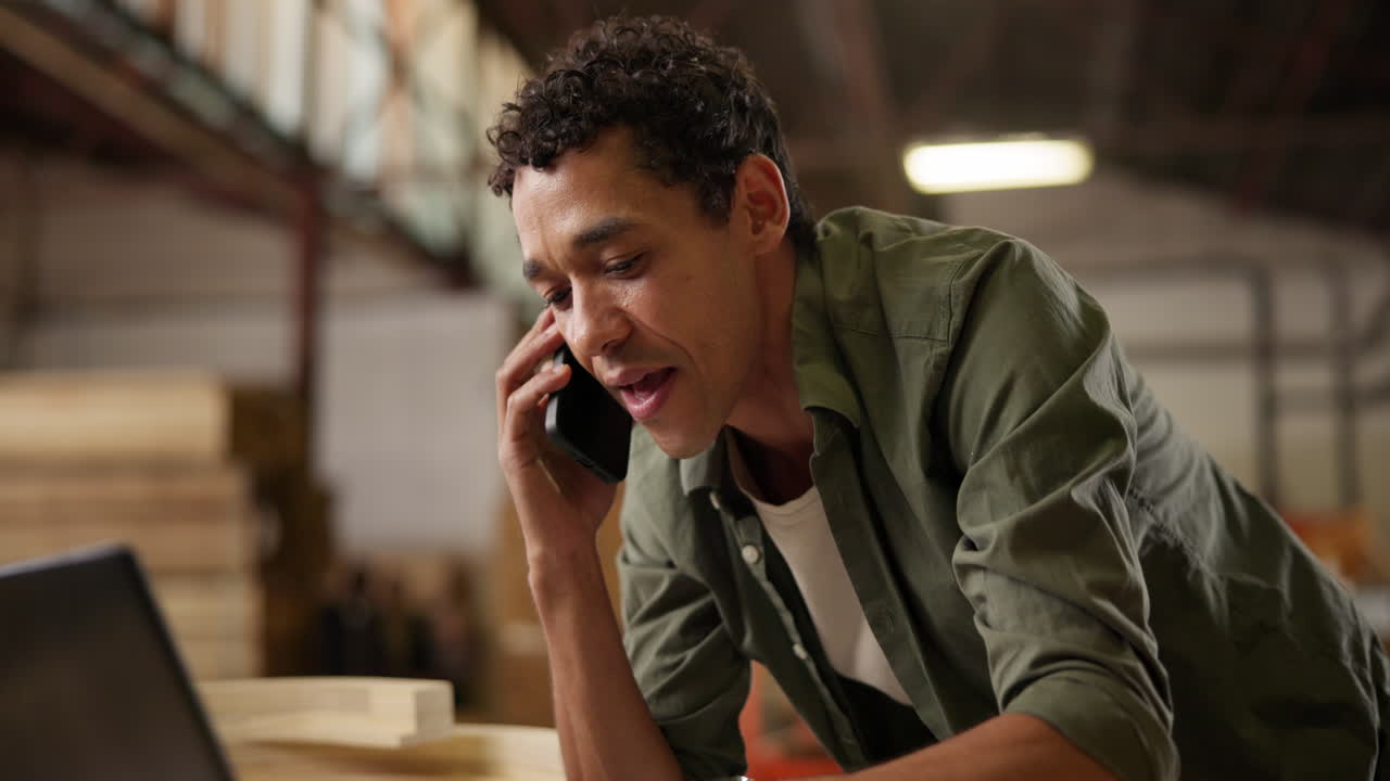 Man using cell phone and laptop in warehouse