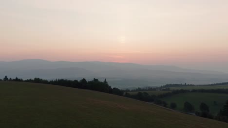 Drone-shot-of-sunrise-above-hills,-forest-and-mountains-in-Czech-countryside