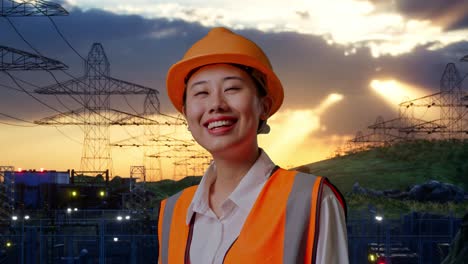 close up side view of asian female engineer with safety helmet looking around while standing near high voltage tower