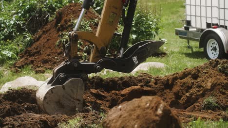 excavadora excavando con tanques de agua y remolque en segundo plano.