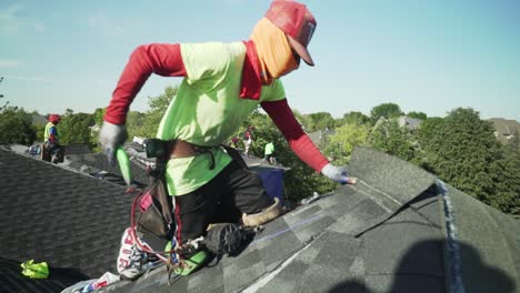 slow motion van bouwvakker die nieuwe dakshingles op een huis installeert