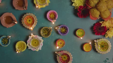 fotografía cenital de lámparas de aceite diya celebrando el festival de diwali ardiendo sobre fondo verde.