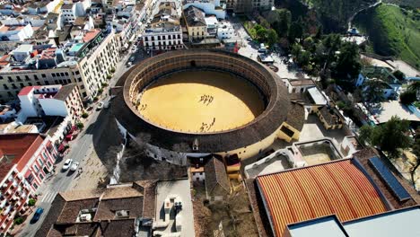 Aerial-tilt-up-view-of-Ronda-city-in-Spain-on-sunny-day-by-green-mountians