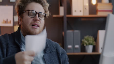 man looking tired while reading documents in the office.