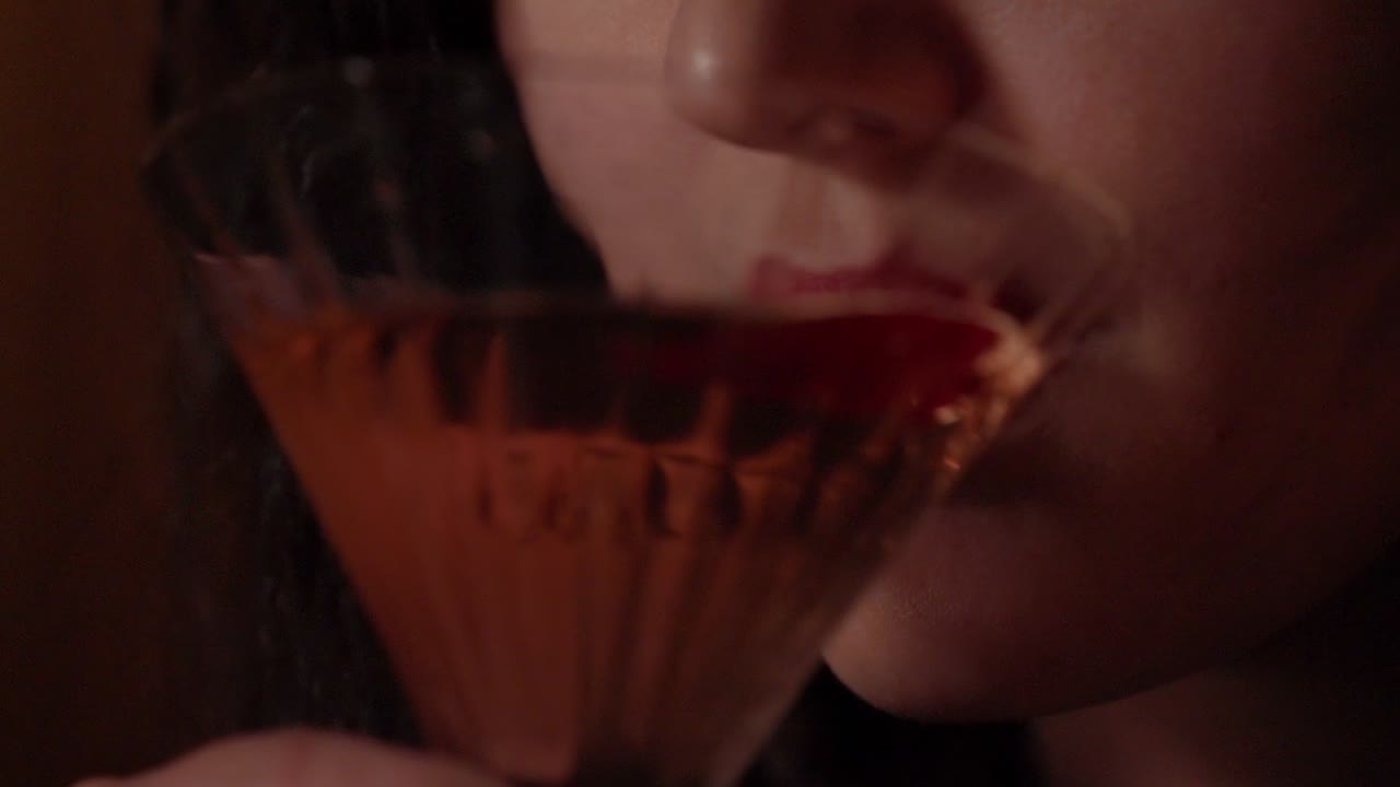A pretty young woman drinks a martini.