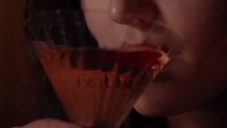 a pretty young woman drinks a martini.