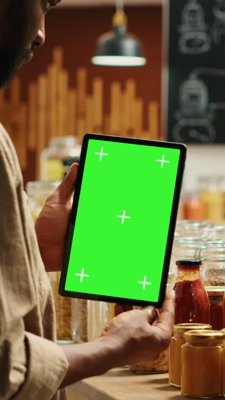 Afrikansk-amerikansk kunde holder tablet med greenscreen-layout i en økologisk butik (stående video)