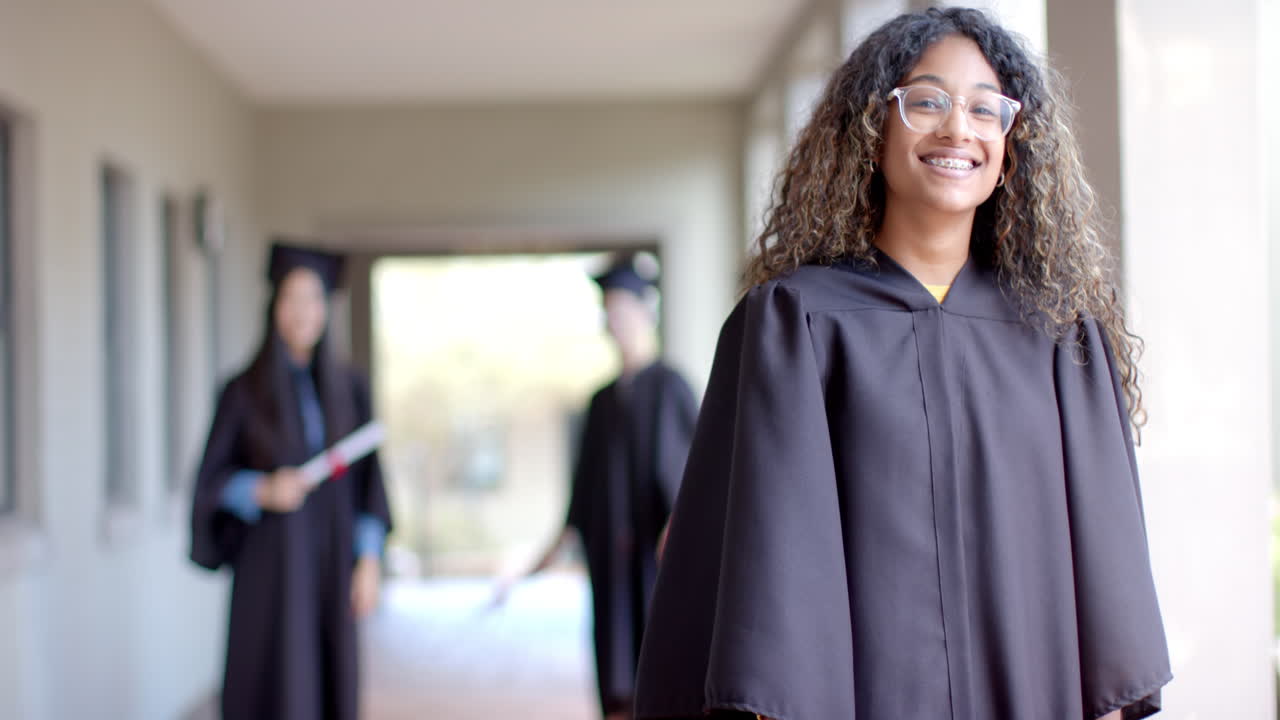 adolescente biracial en vestido de graduación sonríe con orgullo, con espacio para copiar