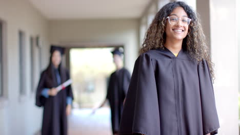 biracial teenage girl in graduation gown smiles proudly, with copy space