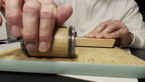 male hand sharpening knife with modern grindstone on wooden board