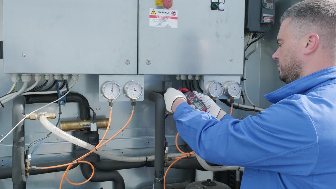 il tecnico controlla le linee elettriche dello scambiatore di calore con le pinze di corrente