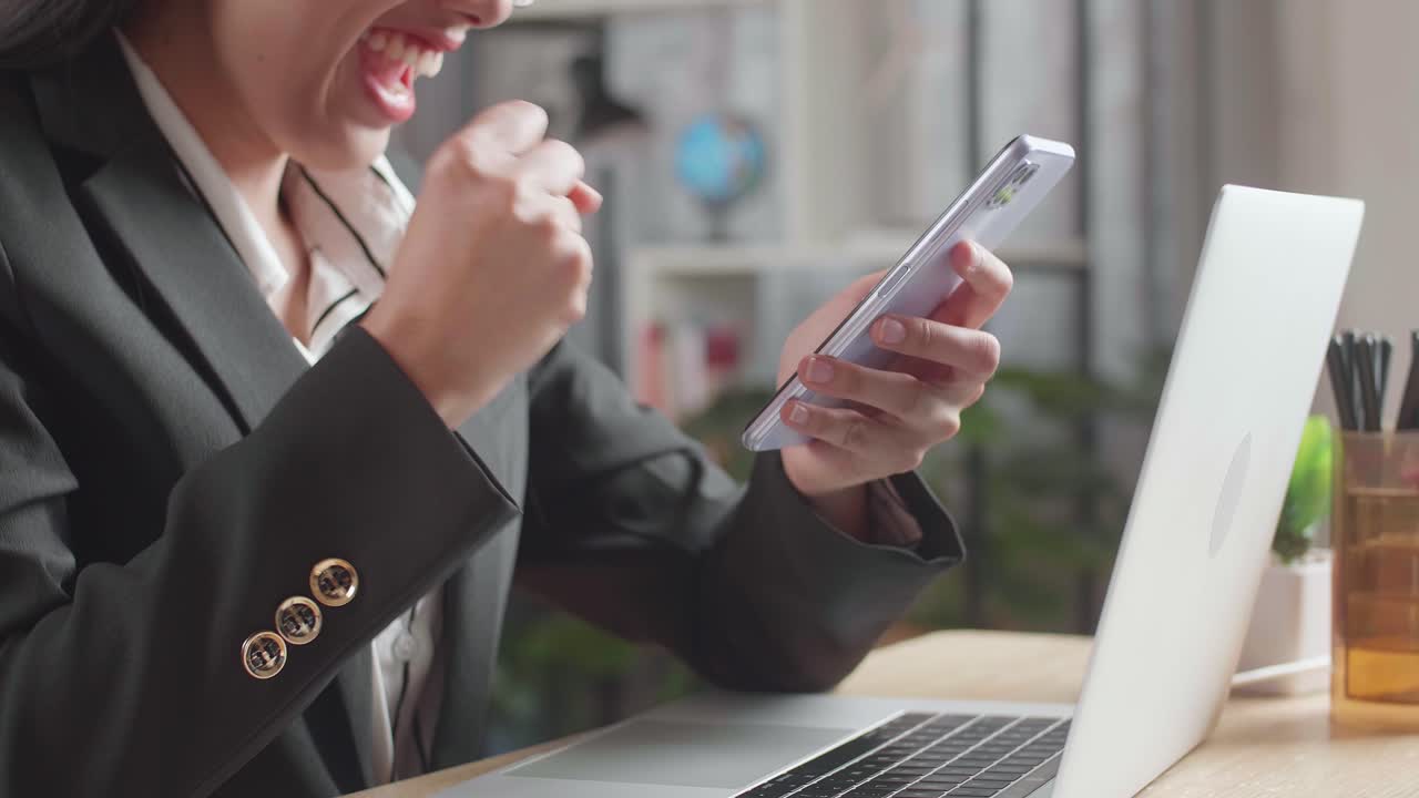 사업가 여성이 스마트폰에서 성공을 축하하고 있습니다.