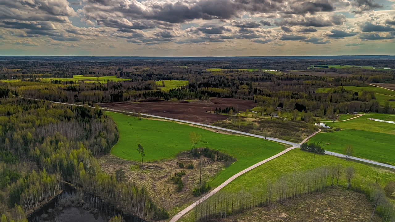 Rural road intersection below a flowing cloudscape time lapse in the European countryside landscape