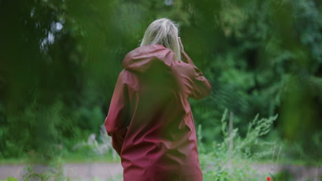 Blonde-Girl-In-red-Hooded-Jacket-Picking-Beautiful-Wildflowers-In-A-Park-In-Netherlands