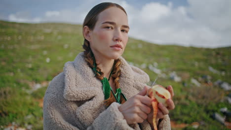 woman peeling apple fruit on outdoor journey. closeup mountain traveler snack