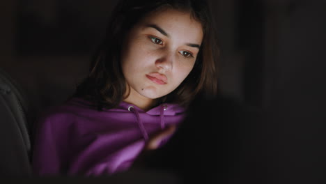adolescente feliz usando una tableta viendo entretenimiento por la noche navegando en línea disfrutando de una noche relajante