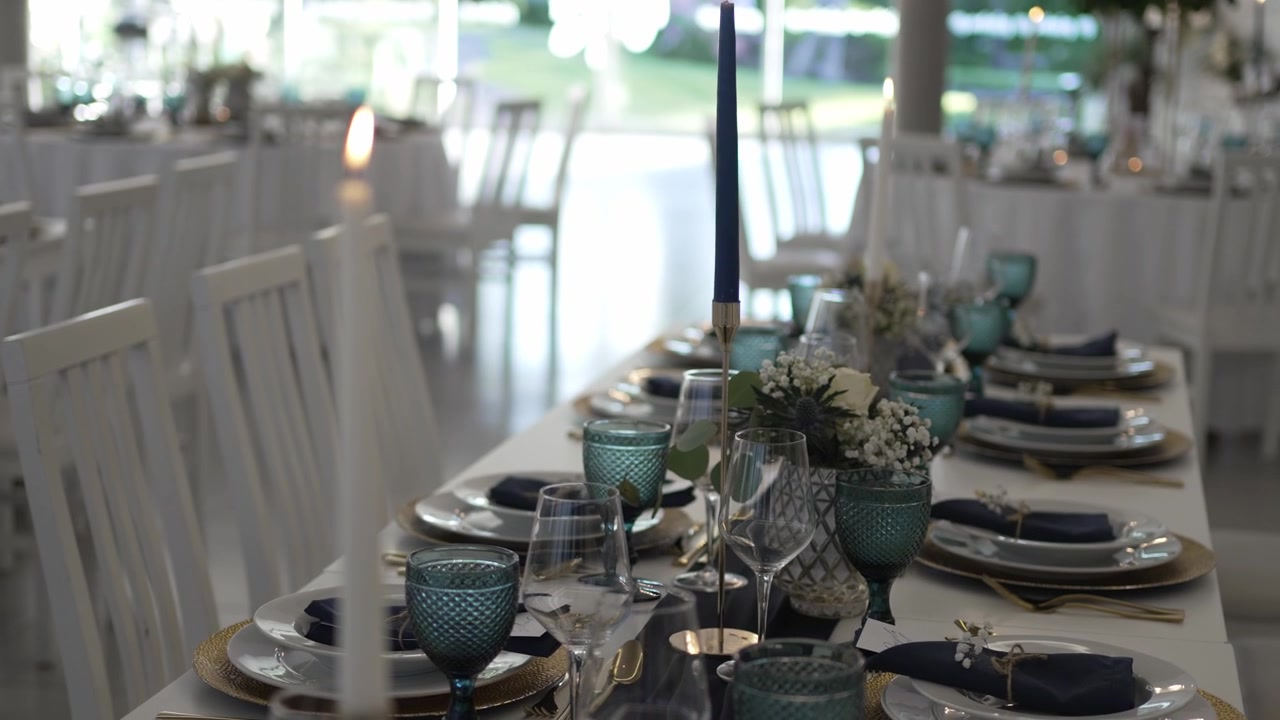 Elegant wedding table setting with blue glassware, floral centerpieces, and candles