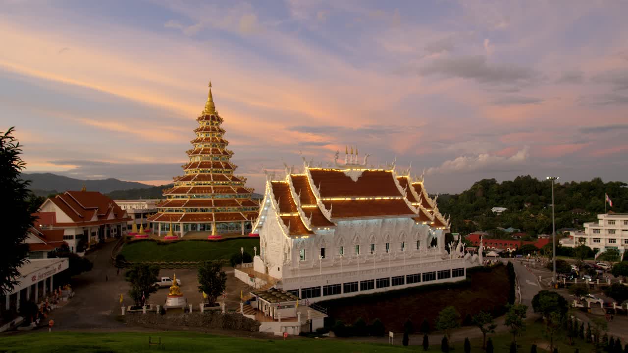 Wat Huay Pla Kang temple complex in Chiang Rai, Thailand, featuring the illuminated Phop Chok Dhamma Chedi and main temple hall at sunset