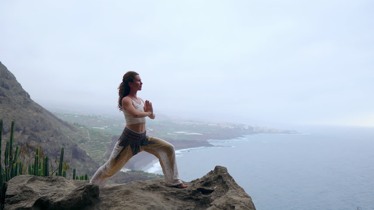 al atardecer junto al océano azul, una joven hace yoga en una orilla rocosa, simbolizando un estilo de vida saludable, armonía y la conexión inherente entre los humanos y la naturaleza