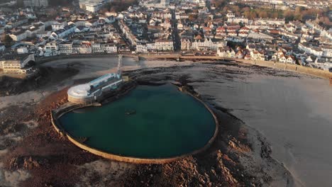 Aerial-shot-tilting-down,-Havre-de-Pas-bathing-pool-at-low-tide,-St-Helier,-Jersey,-Channel-Islands,-4k