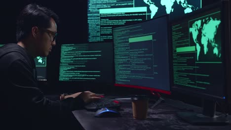 asian male hacker hacking with multiple computer screens in dark room
