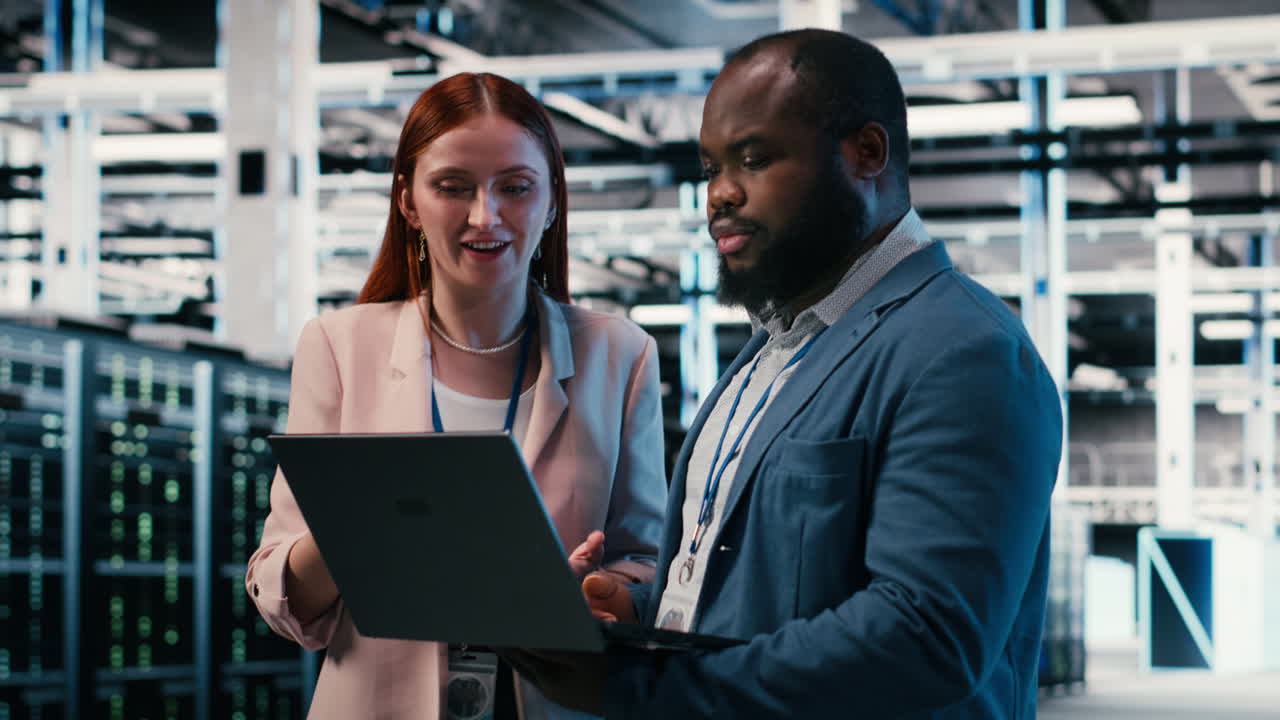 Diverse IT Engineers Discussing Data Center Operations on Laptop