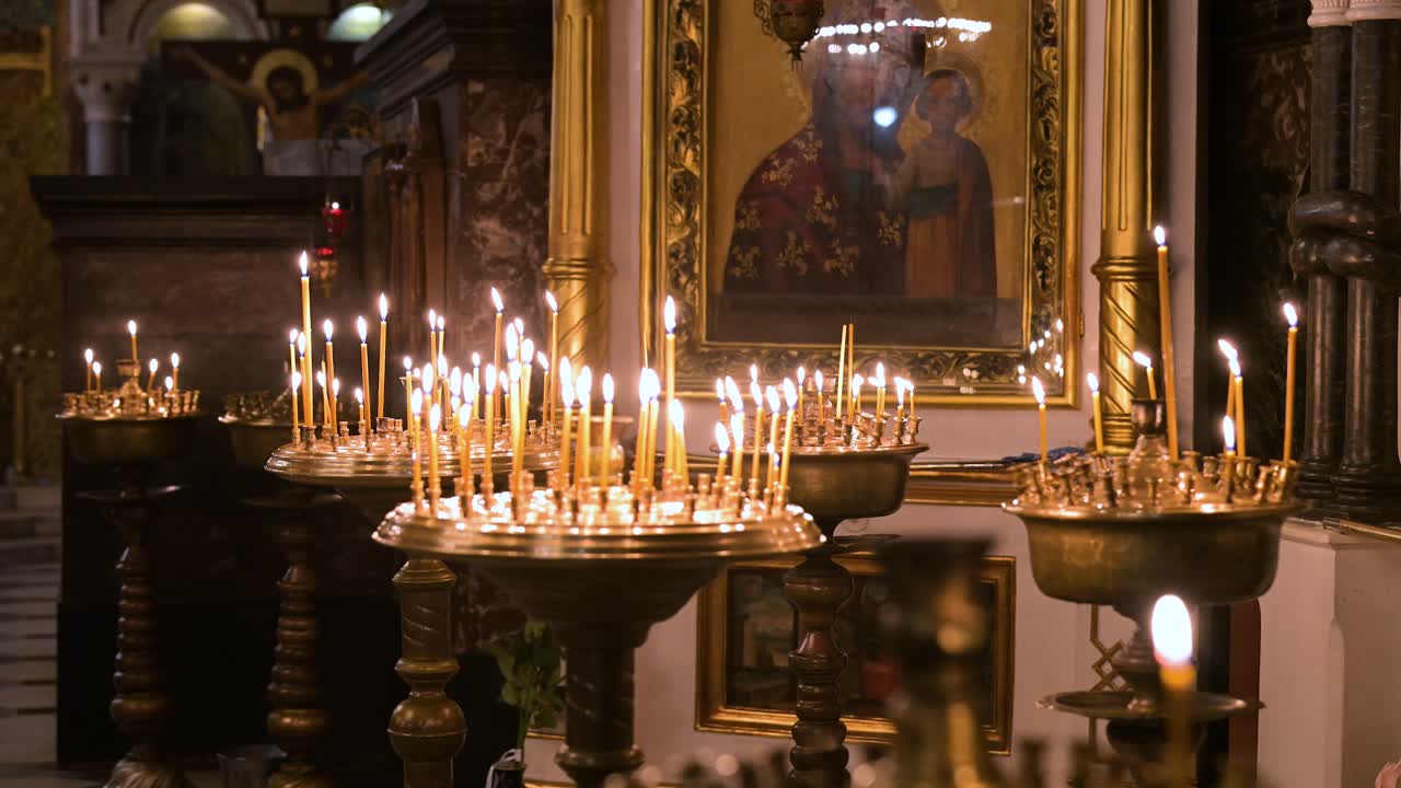 A serene atmosphere fills the historic St. Volodymyr's Cathedral in Kyiv as candlelight glows before a sacred Orthodox icon. The flickering flames create a peaceful and contemplative ambiance.