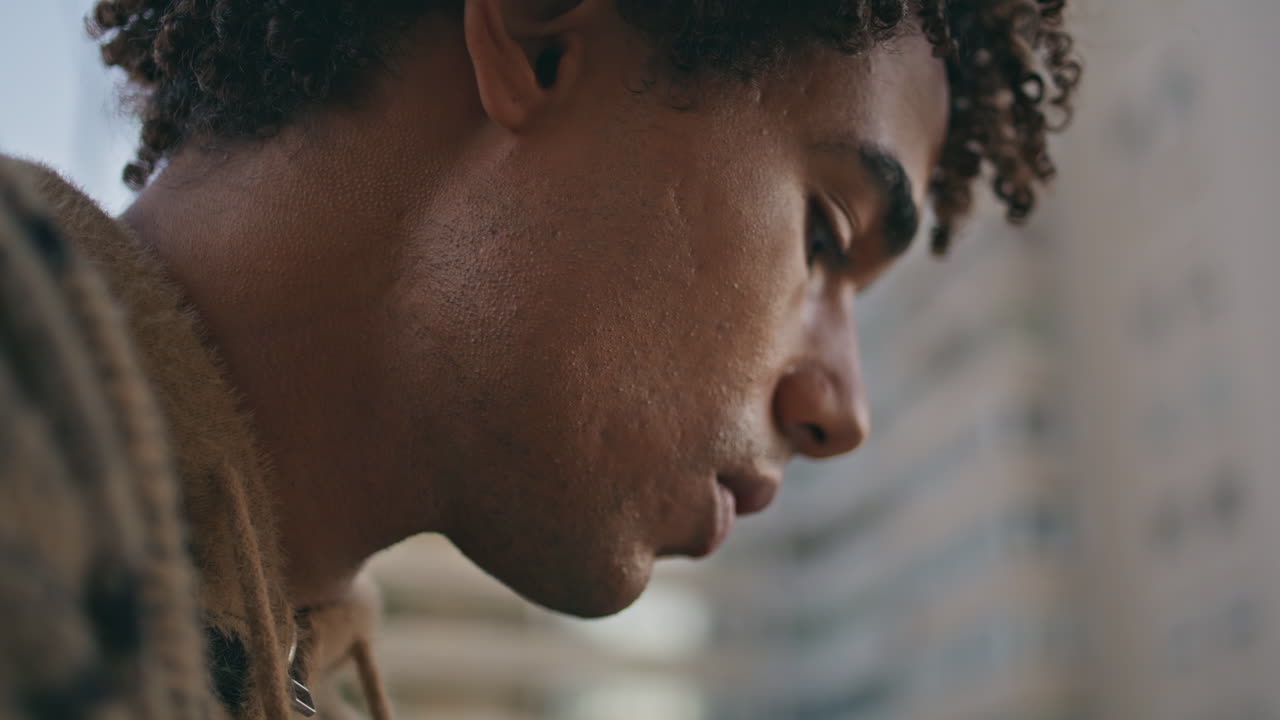 Close-up do rosto de um homem bronzeado olhando para a câmera com um olhar intenso ao ar livre. Homem hispânico.