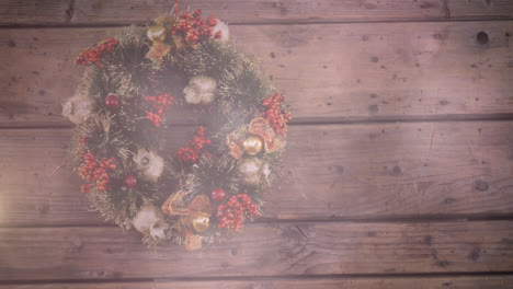 digital composition of spots of light against christmas wreath decoration on wooden surface