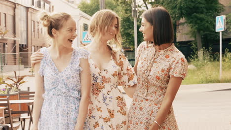 three happy women friends walking in city