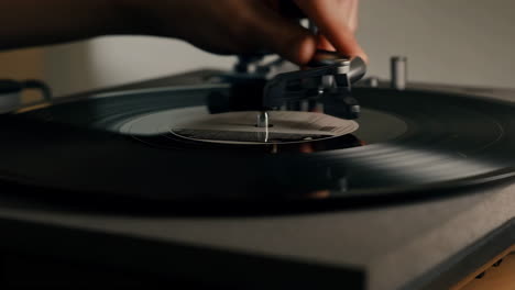 a hand playing a vinyl record on a turntable