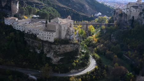 the stunning colors of autumn foliage surround the historic parador hotel and san pablo bridge, set within the dramatic huecar gorge landscape of cuenca, spain.