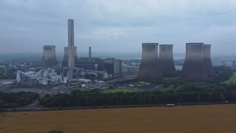 Imposing-concrete-cooling-tower-power-station-farmland-countryside-aerial-view-slow-forward-rising-shot