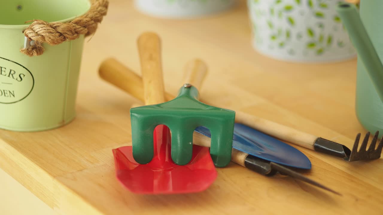 Close-up of gardening tools and a watering can on a wooden surface