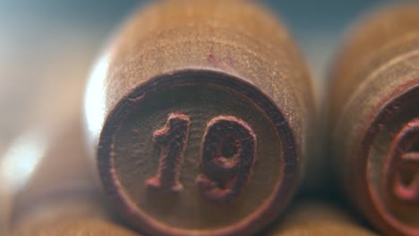 macro cinematográfico plano suave de barriles de madera de bingo en una fila, figuras de madera, números antiguos juego de mesa vintage, número de la suerte 19, cámara lenta, movimiento de gimbal comercial de 4k, iluminación de ensueño, inclinación hacia arriba