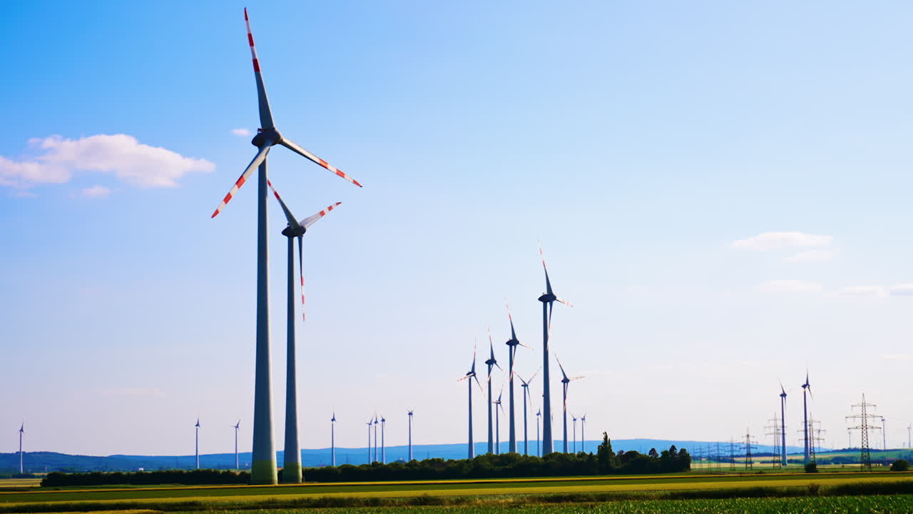 Turbines produce clean energy. Wind turbines stand tall in a green landscape, harnessing wind energy under a clear blue sky during daylight hours