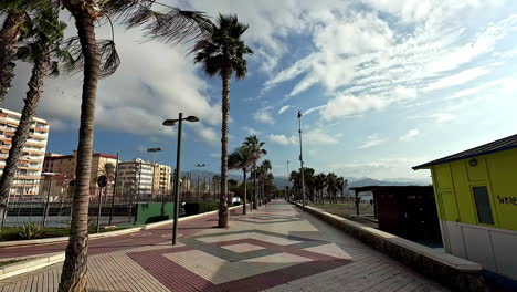 coastal boulevard walkway lined with palm trees and hotels in malaga - spain