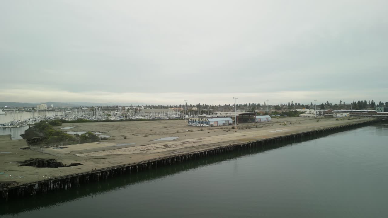 Drone footage captures the Encinal Basin at Mariner Square, with boats anchored in the serene waters and the Alameda shoreline in view.