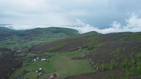 Vuelo-Aéreo-Sobre-La-Ciudad-De-Banska-Bystrica,-Impresionantes-Montañas-Del-Bajo-Tatra-Cubiertas-De-Nubes-Blancas-Bajas-Y-Densos-Bosques,-Eslovaquia