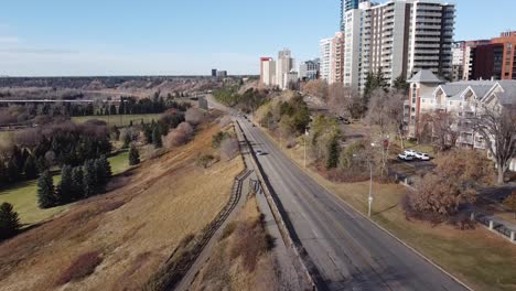 Panorámica-Aérea-Desde-La-Autopista-Hasta-El-Valle-Residencial-De-Los-Condominios-De-Las-Torres-Junto-Al-Borde-Del-Parque-En-Un-Cielo-Azul-Claro-Día-De-Otoño-Con-Tráfico-Ligero-Y-Escaleras-Que-Conducen-Al-Campo-De-Golf-De-Manera-Privada-Vip-De-Lujo