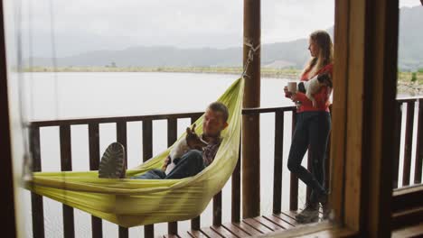 caucasian couple spending time at home, both holding a dog outside the cabin