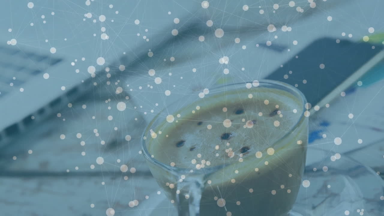 Glass coffee cup floating above wooden desk, showing laptop keyboard, smartphone, network overlay