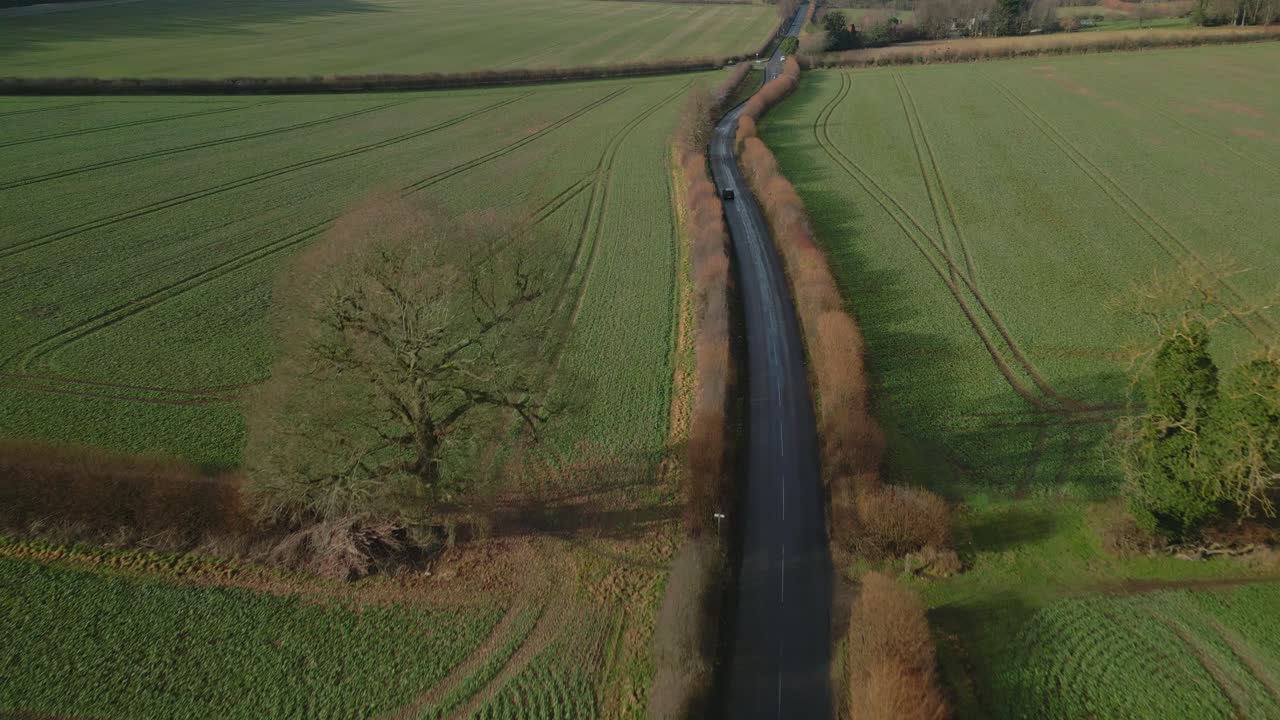 석양에 겨울에 영국 시골 길에서 자동차의 아름다운 공중 드론 샷