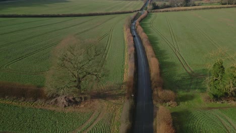 beautiful aerial drone shot of a car in an uk country road in the winter at sunset