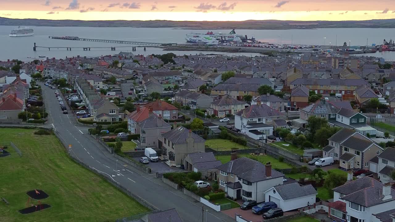 Early morning aerial view across Holyhead coastal suburban town under glowing sunrise skyline