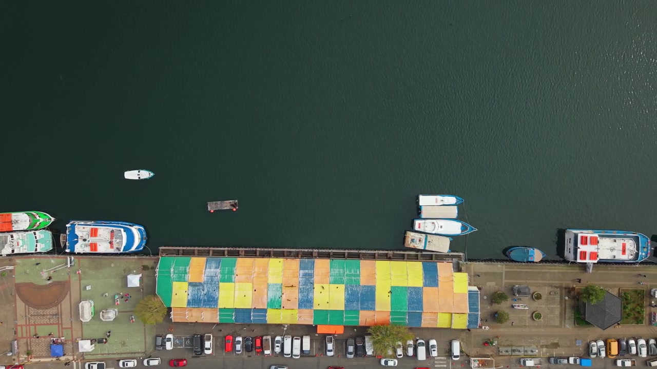 Top down aerial view of the Valdivia River Fair in Chile near Schuster Pier, with tourist boats cruising along the Calle Calle River