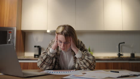 a young woman is tired of work and takes up her head from fatigue sitting at a table in the living room. work from home